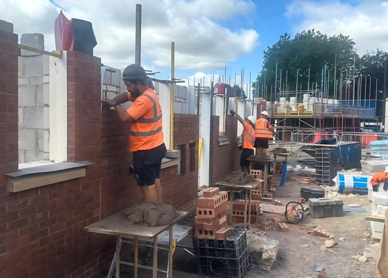 a group of construction workers building a red brick house in the uk